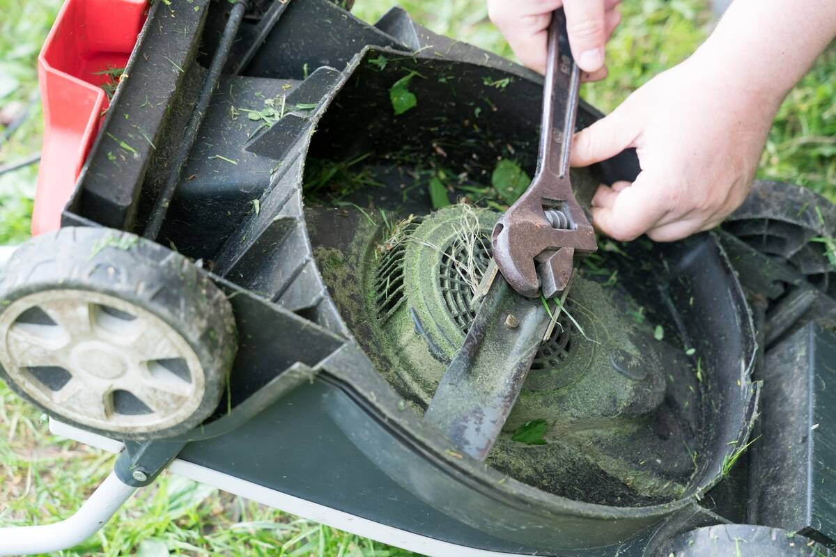 hands servicing bottom of lawn mower