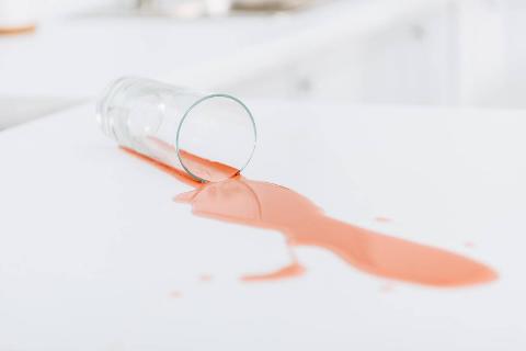 A spilled glass or orange drink on a white counter. 