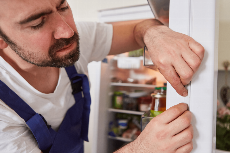 A man adjusting a fridge door seal.