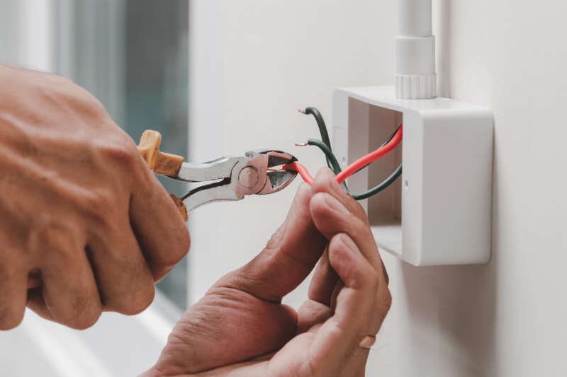 A person clipping wires in an outlet.
