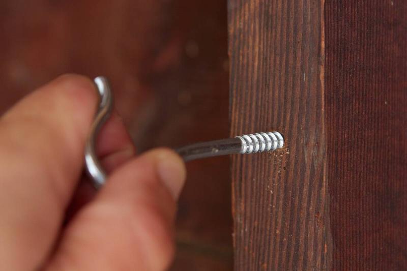 Putting the screw in the hole in the wood. 