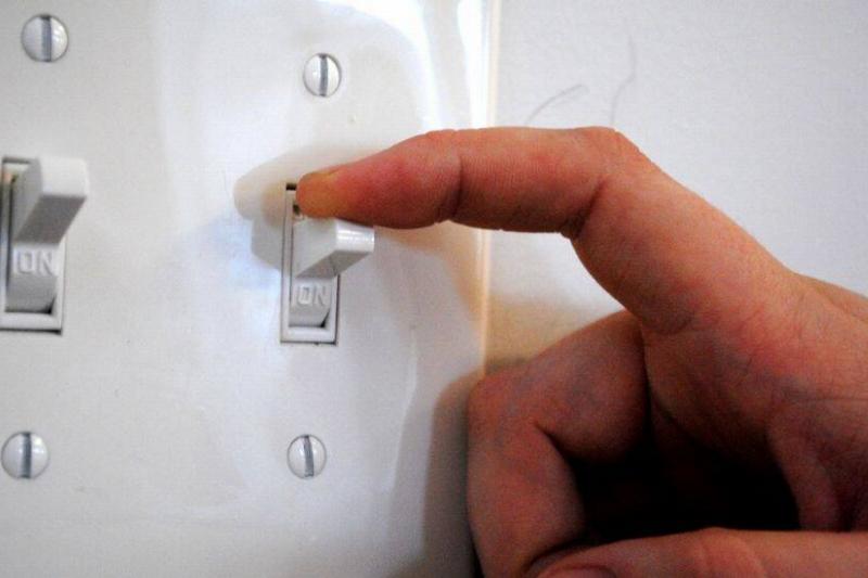 Finger turning off the light switch. 