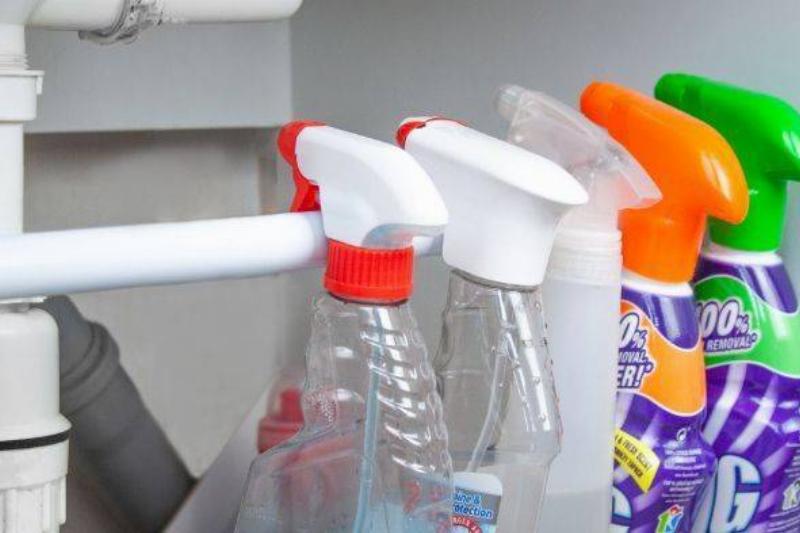 Bottles hanging on tension rod under sink.