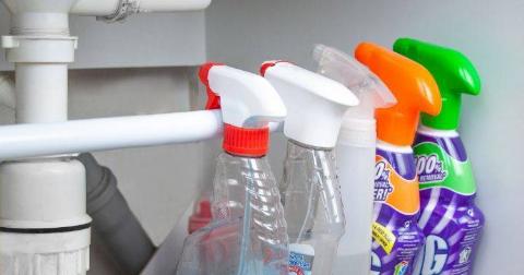 Bottles hanging on tension rod under sink.