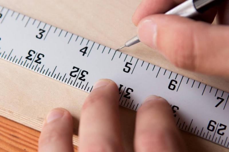 Marking a piece of wood with a ruler and pencil.