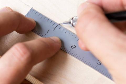 Making a mark on the piece of wood.