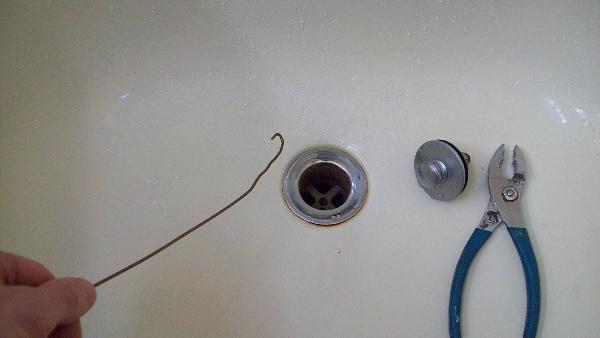 A wire hanger by a drain. 