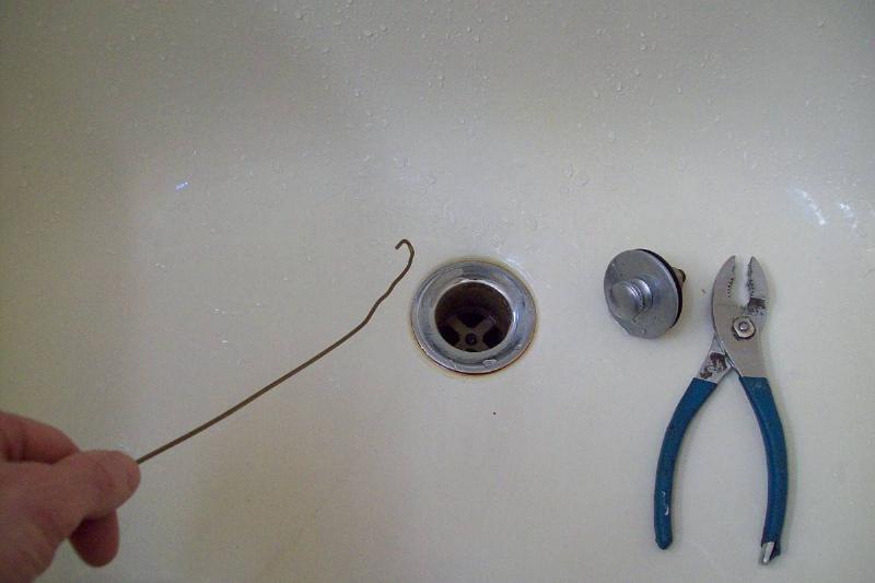 A wire hanger by a drain. 