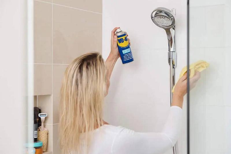 Woman spraying WD-40 on shower.
