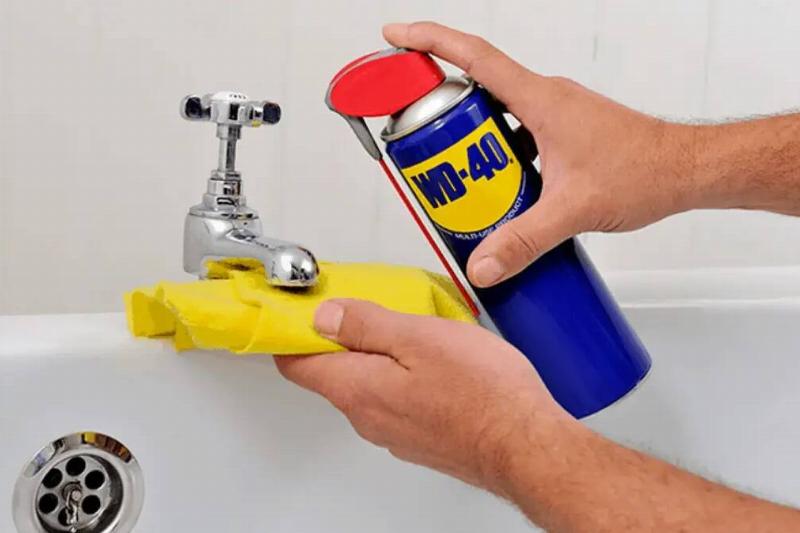 Spraying WD-40 on faucet.