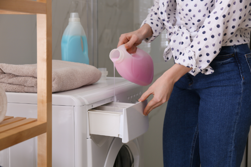 Pouring laundry detergent in machine.