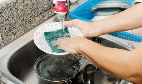 Washing dishes with a sponge.