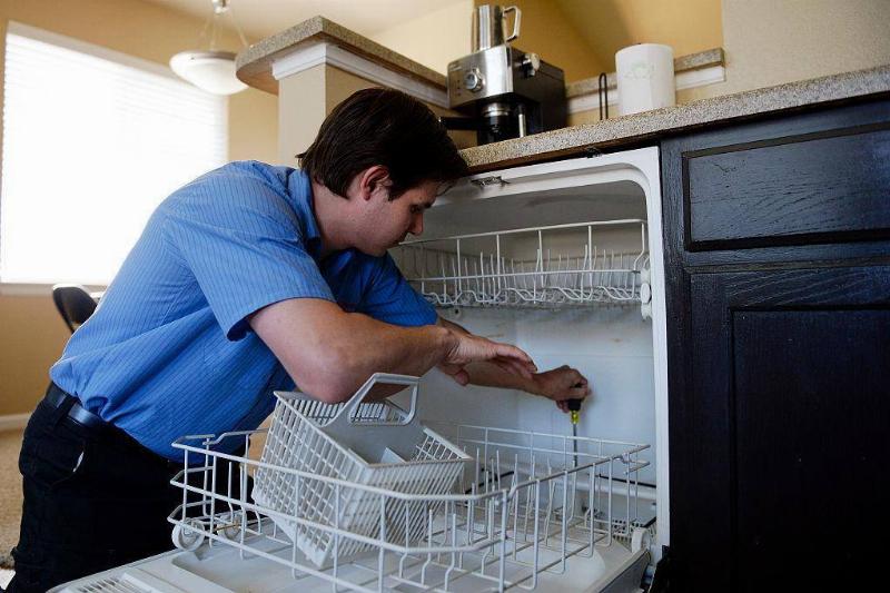 Technician fixing dishwasher.