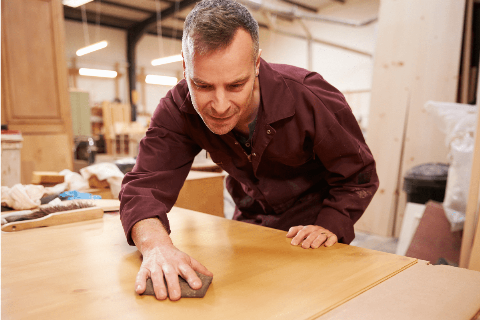 Man sanding wood table.