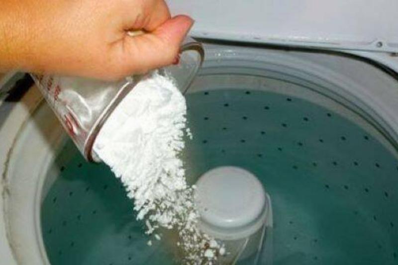 Pouring baking soda in washing machine.