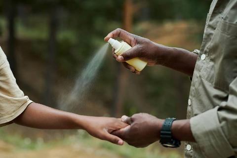 Spraying bug spray on arm.