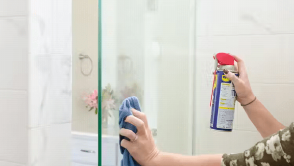 Spraying WD-40 on shower.