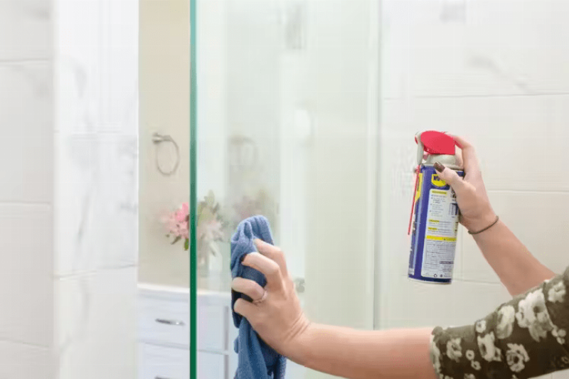 Spraying WD-40 on shower.