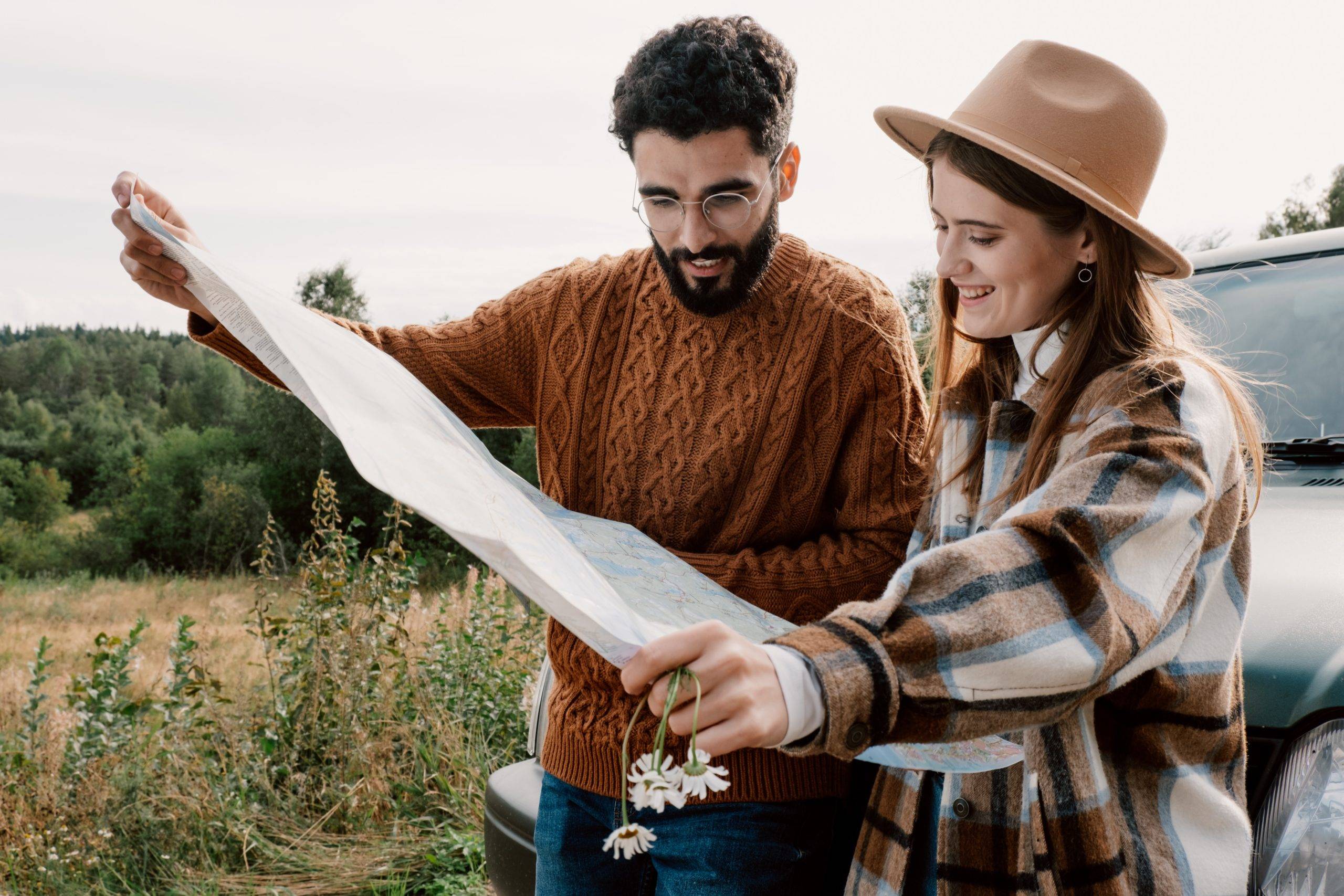 couple leaning on hood of car smiling at map