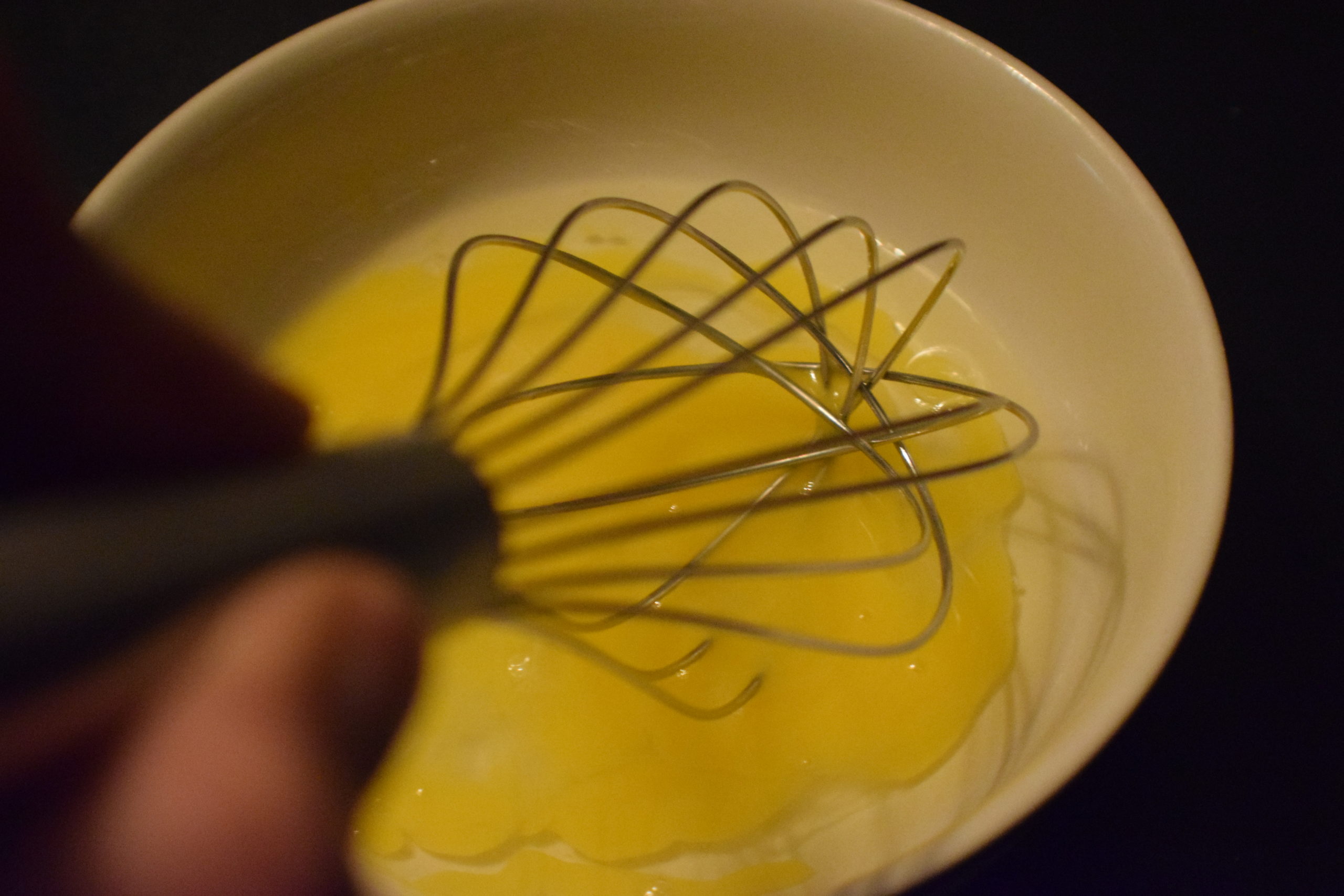 whisking an egg in a white bowl