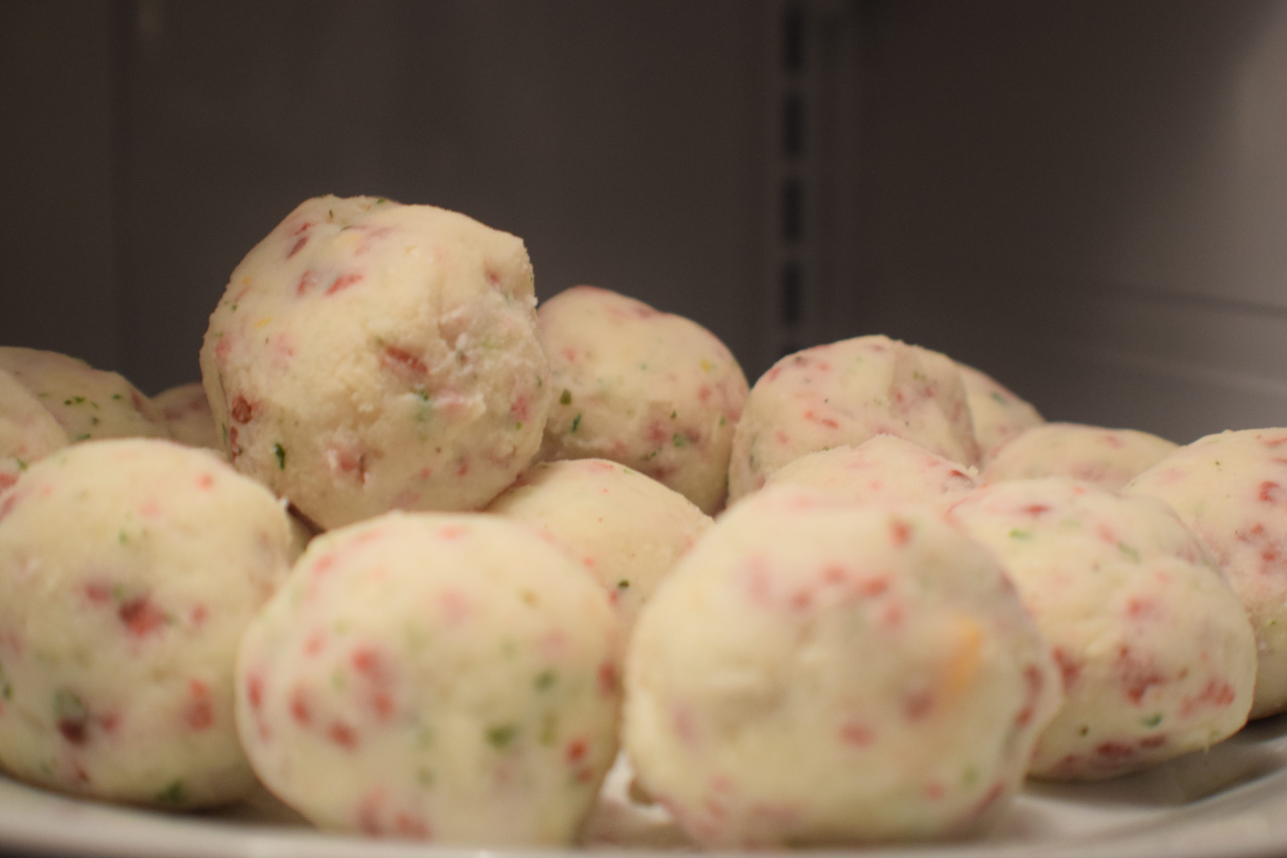 mashed potato balls on a white plate in a fridge