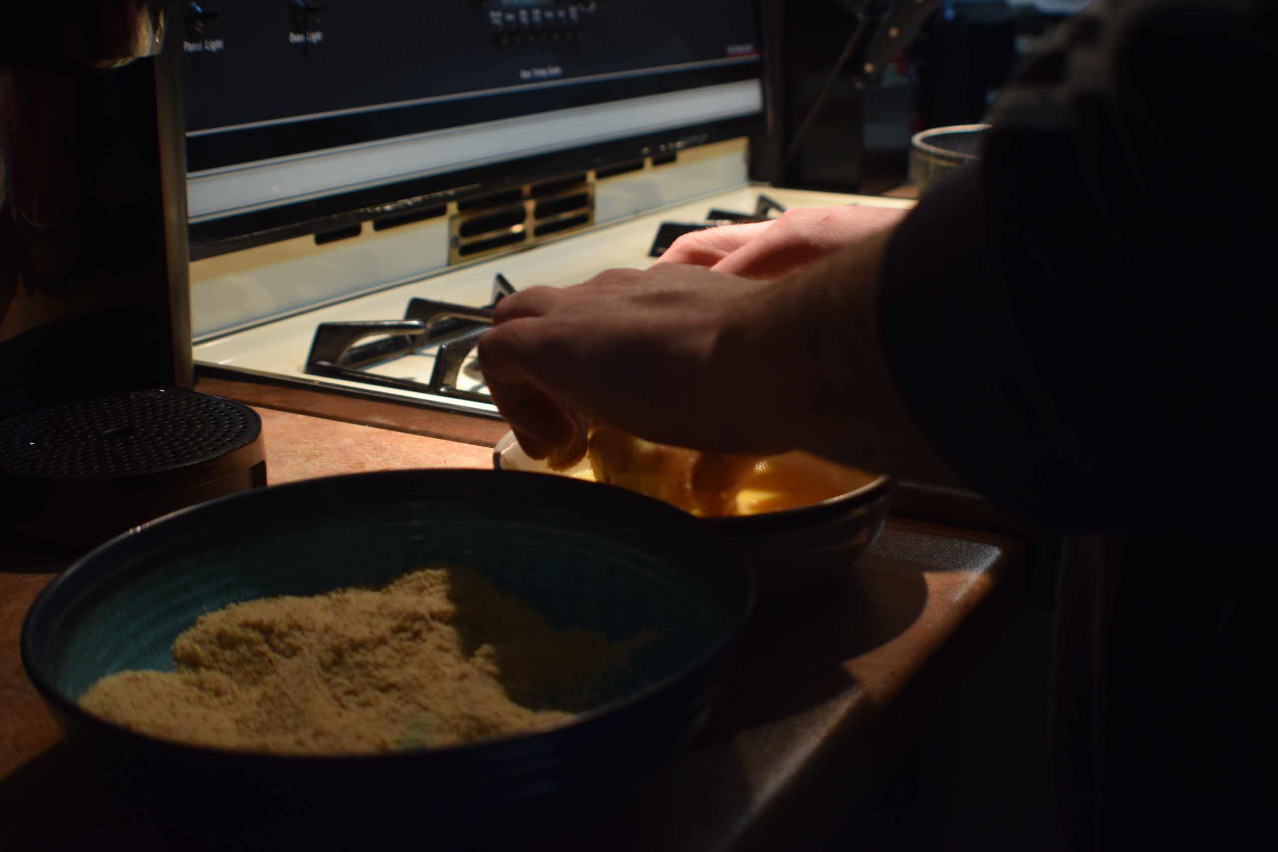 man hands rolling food in egg and breadcrumb