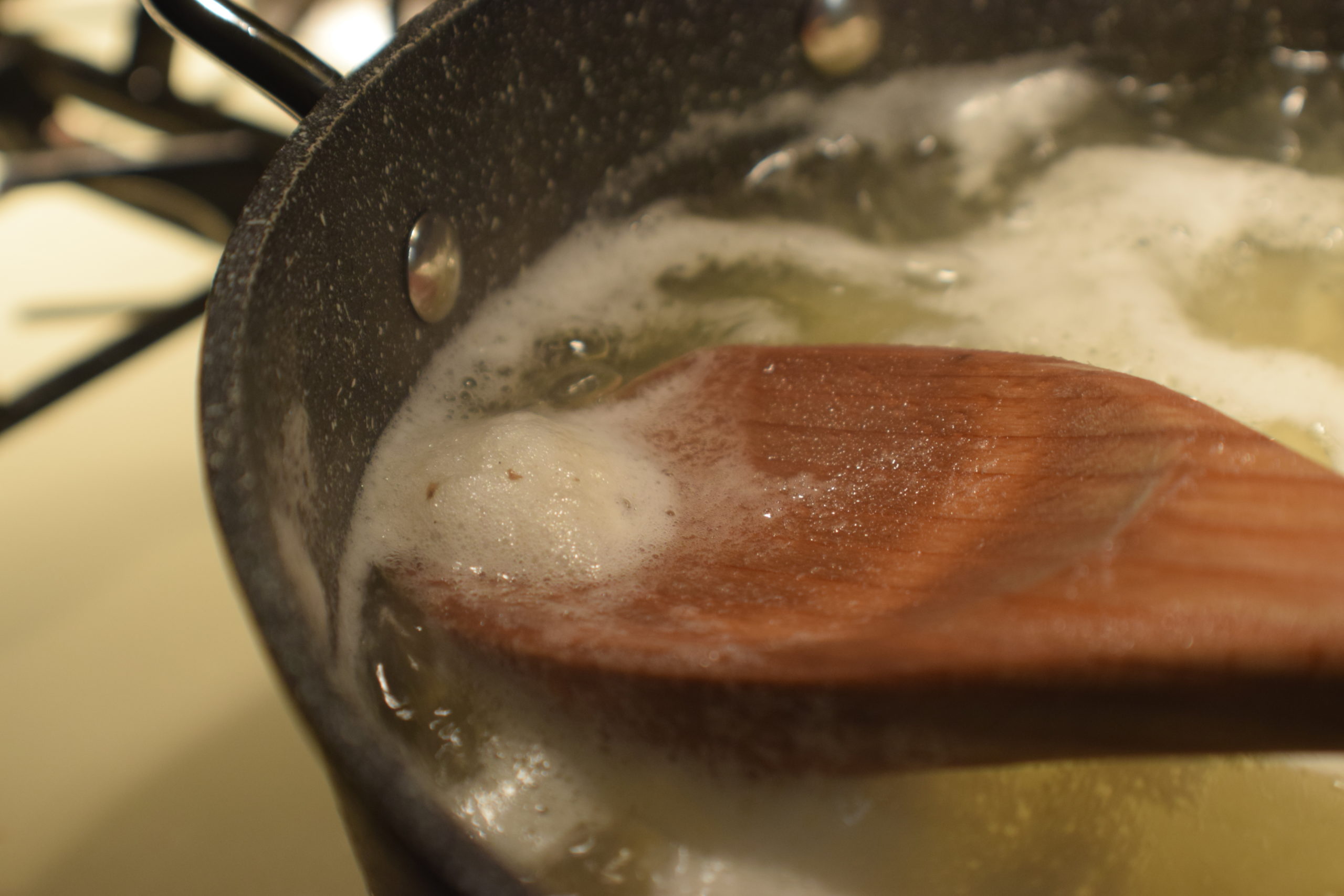 skimming starch from boiling water with wooden spoon