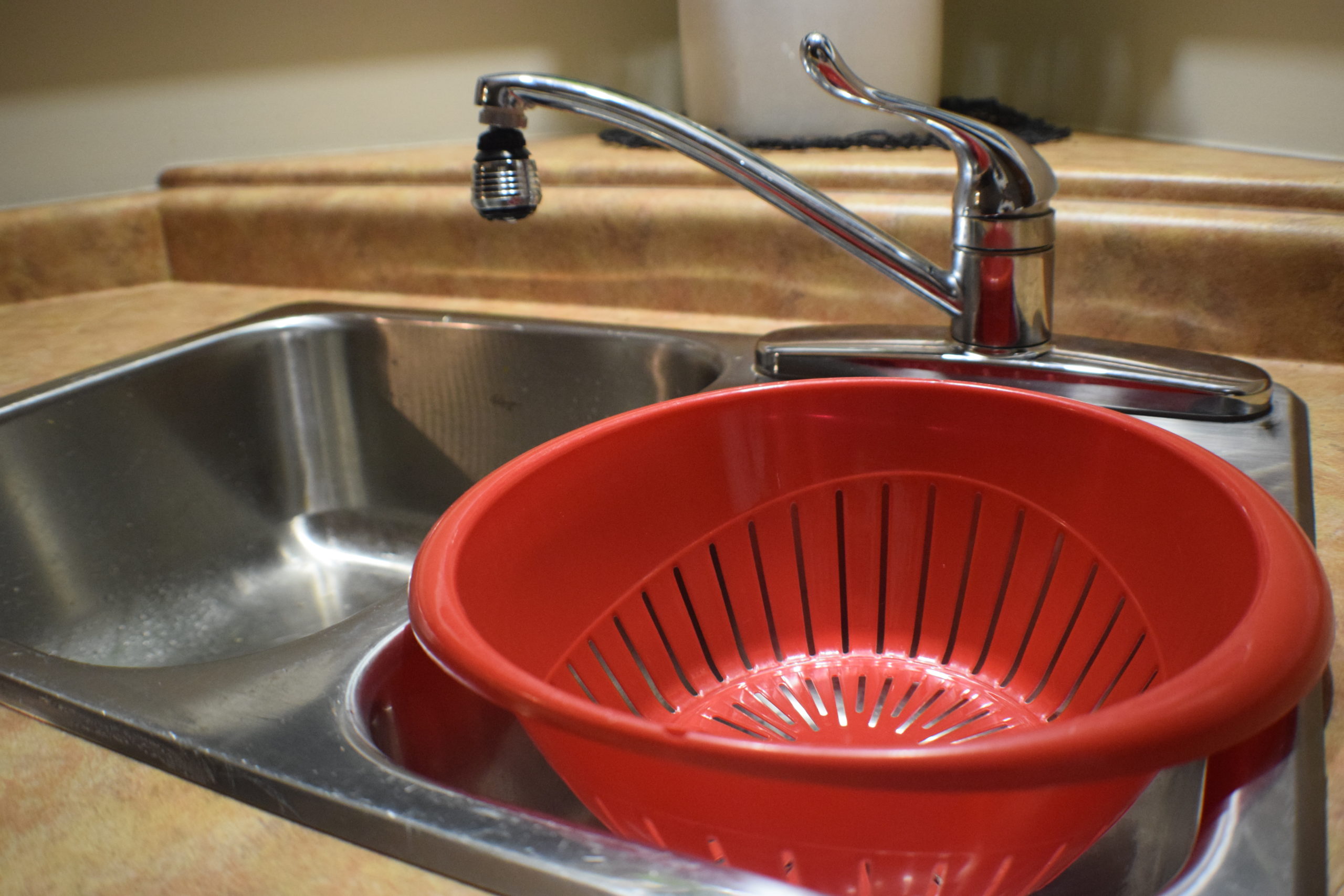 red strainer in small side of sink