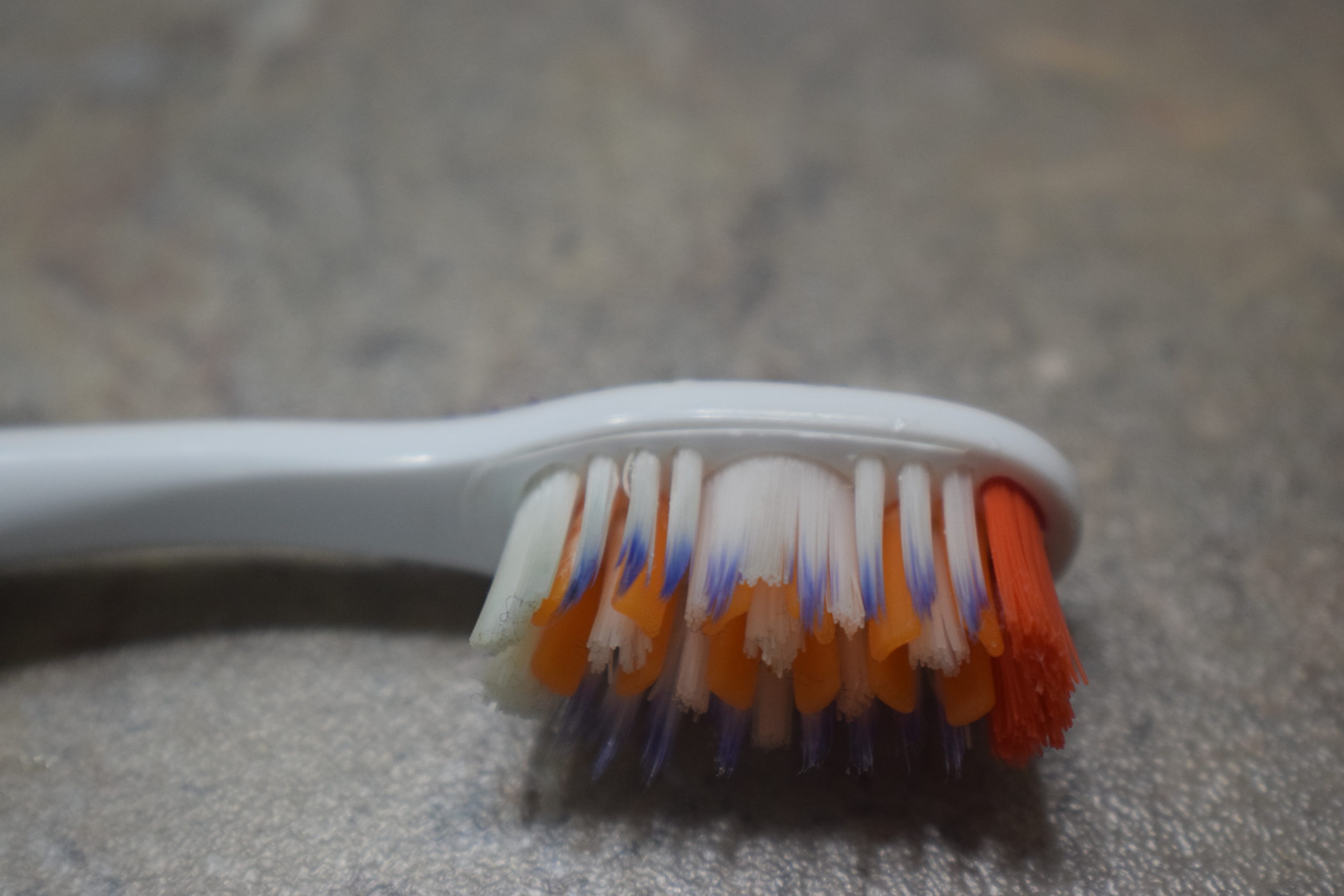 Orange, purple and white bristles on a toothbrush