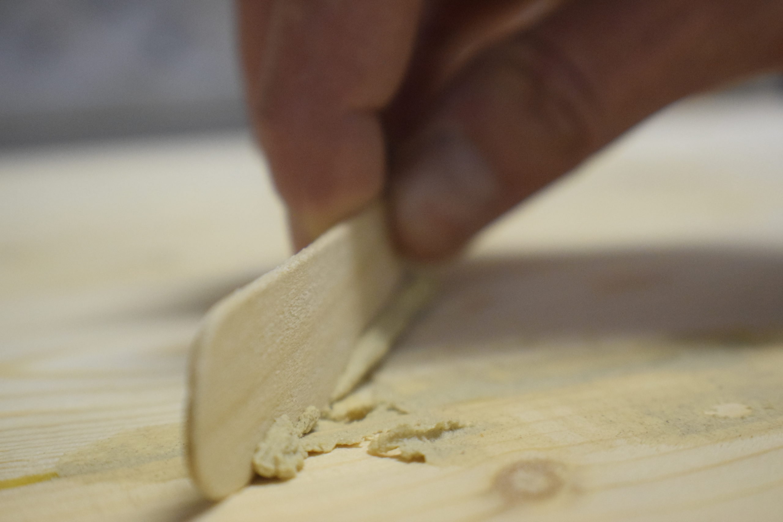 hand using popsicle stick to wipe away excess wood filler on pine wood