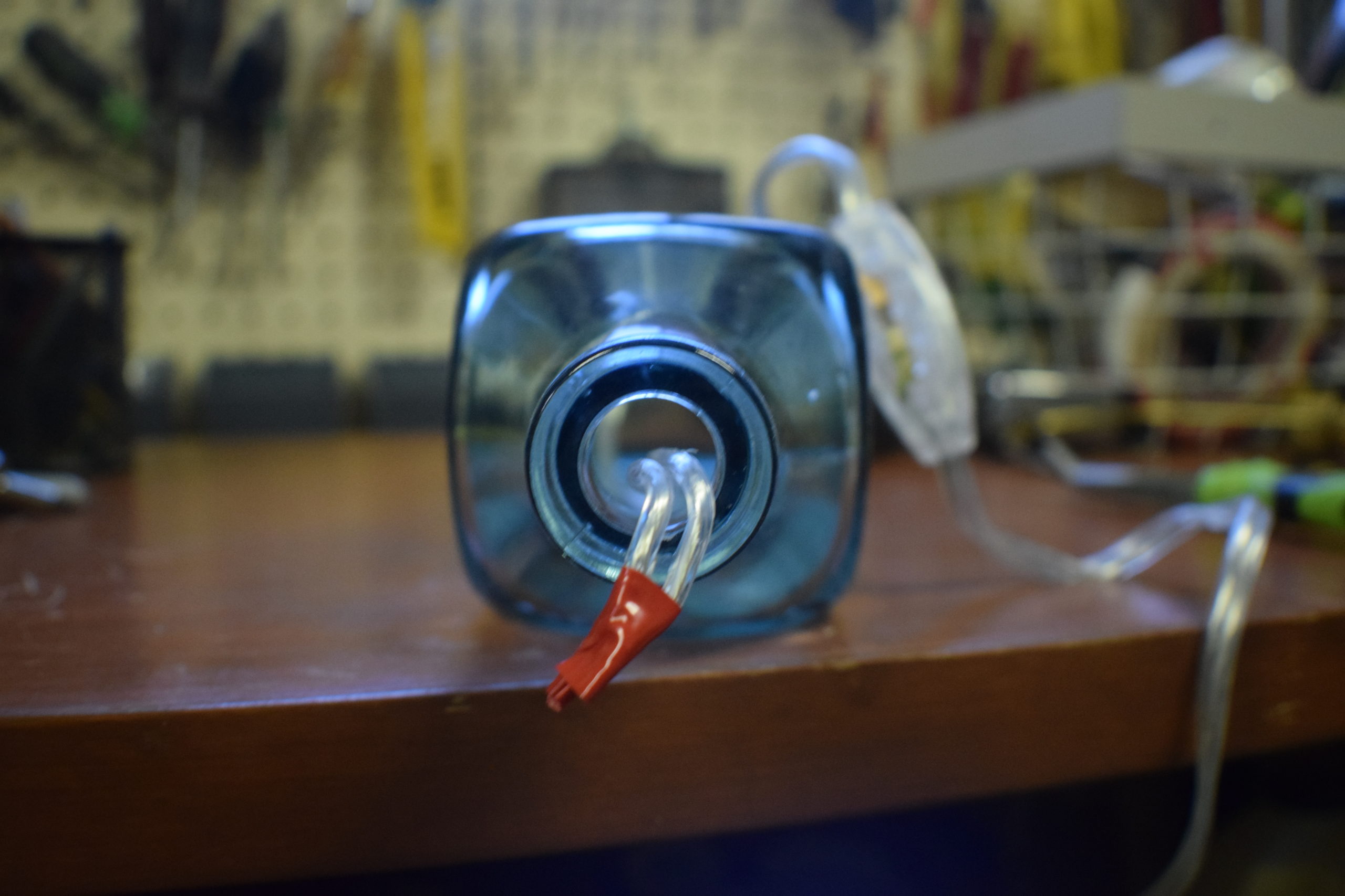 electrical wires with red tape on the end pulled out of a square liquor bottle