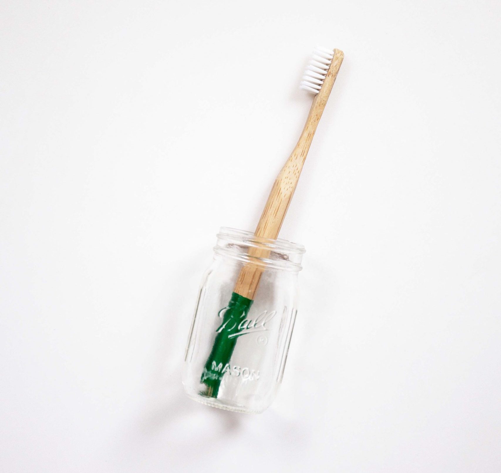 Wood toothbrush in mason jar with green tape