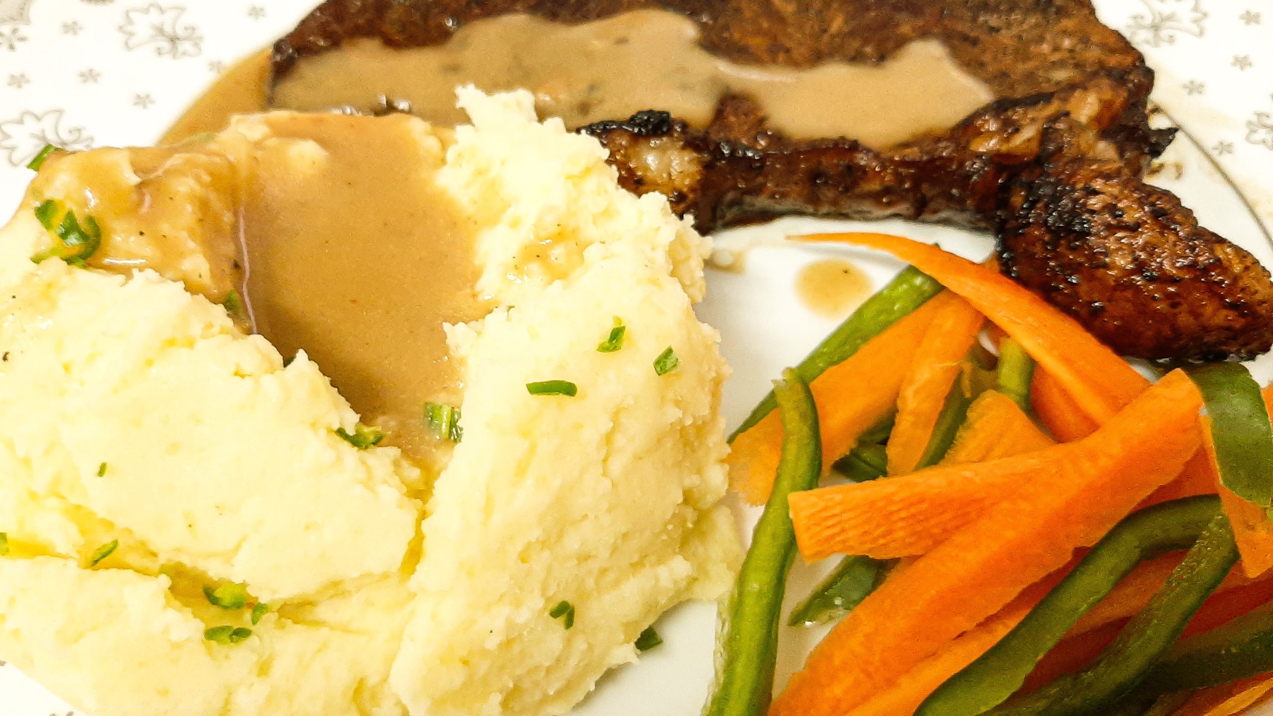 Mashed potatoes, steak and vegetables on a white plate