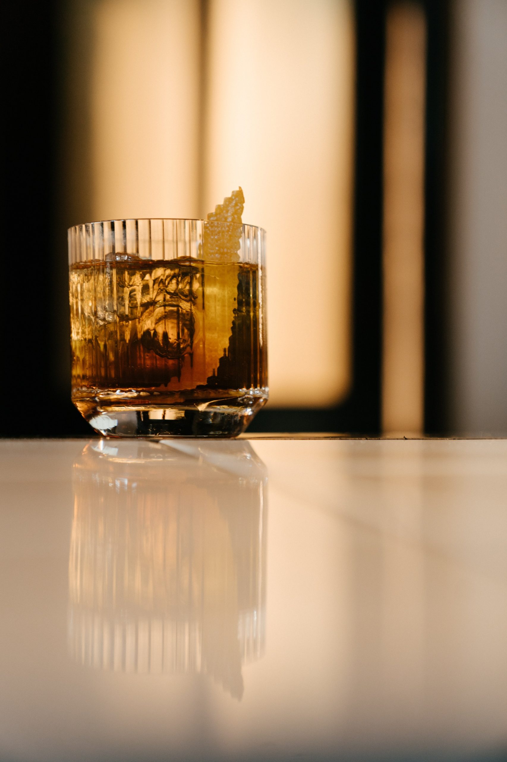 old fashioned whiskey drink in lined glass on a counter with garnis