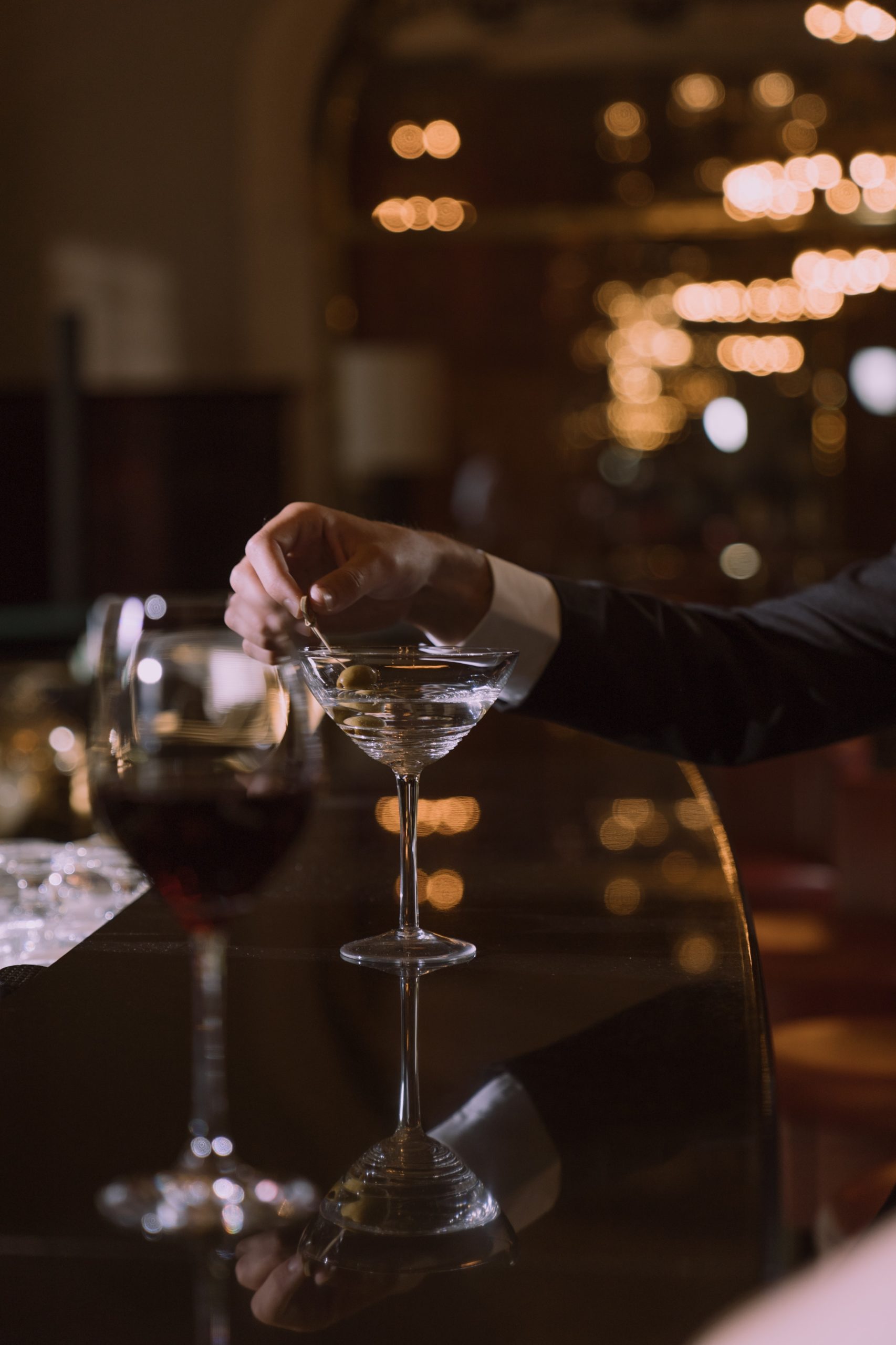 man in a suit stirring martini in a bar
