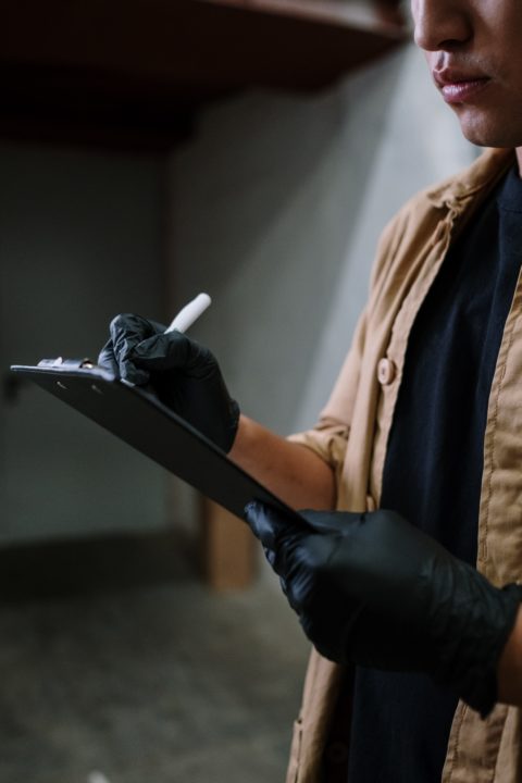 man in checkered shirt with black gloves checking off his list in a shop