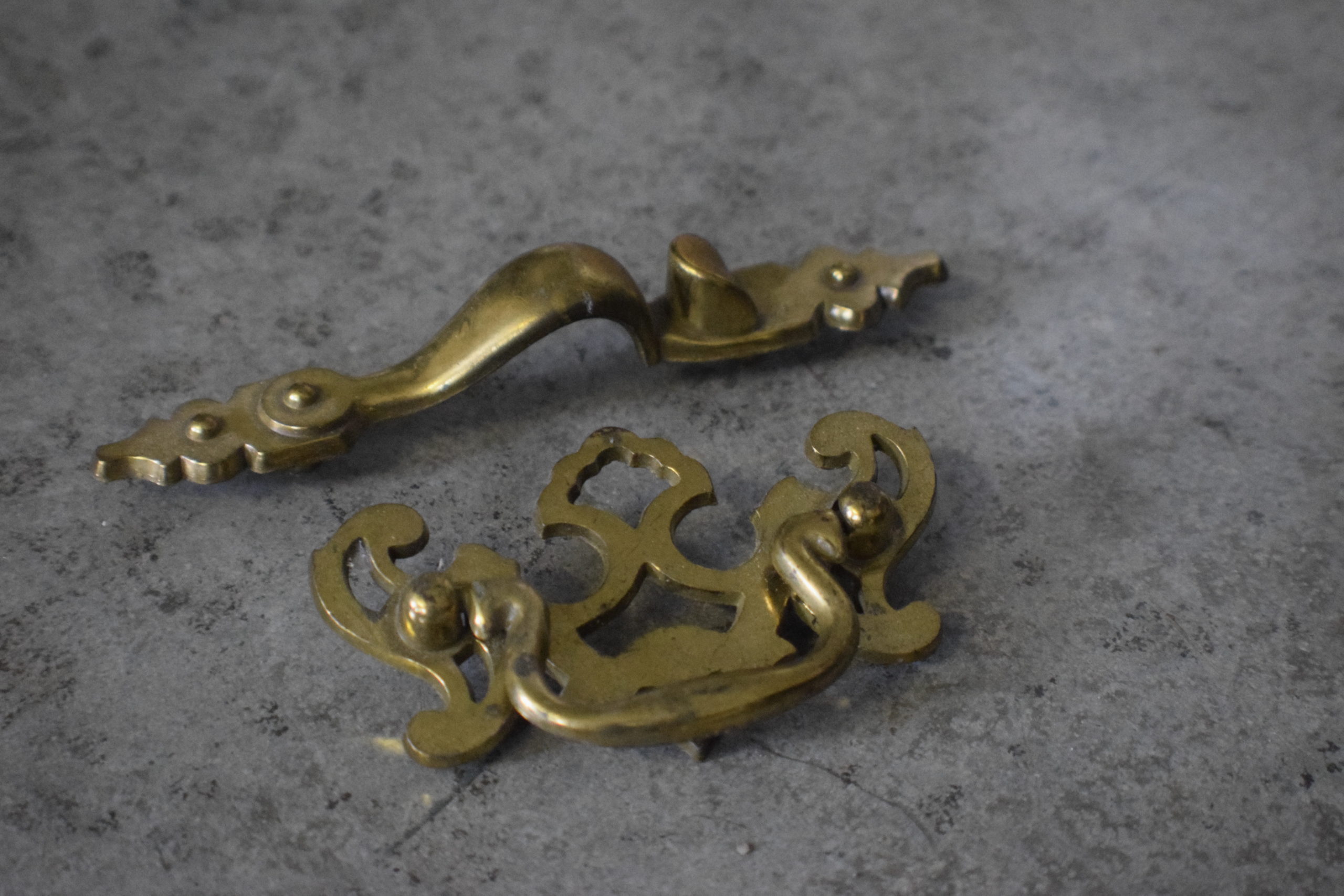 vintage cabinet hardware in gold on cement floor