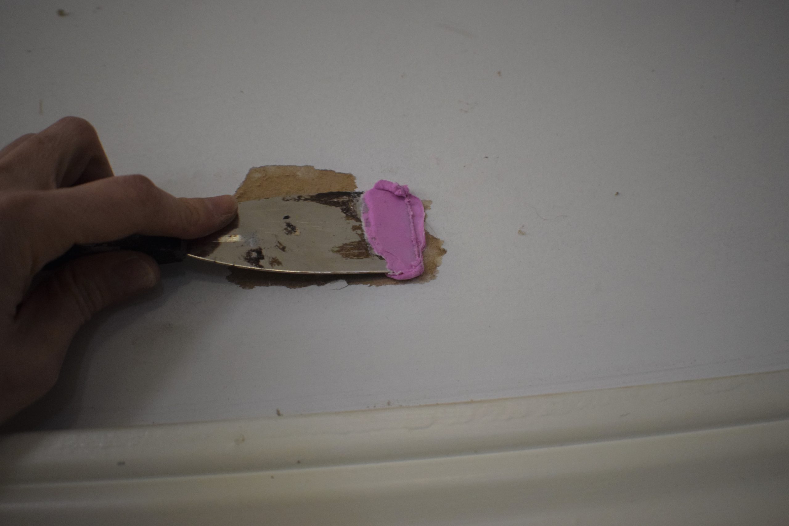 spreading spackling over a wall with a putty knife