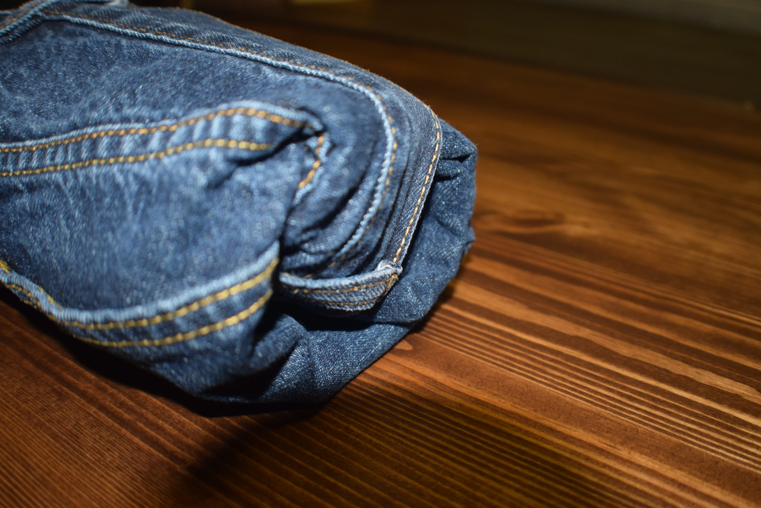 pair of blue jeans rolled up on a wood surface