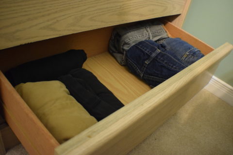 rolled pants in bottom drawer of light wood dresser