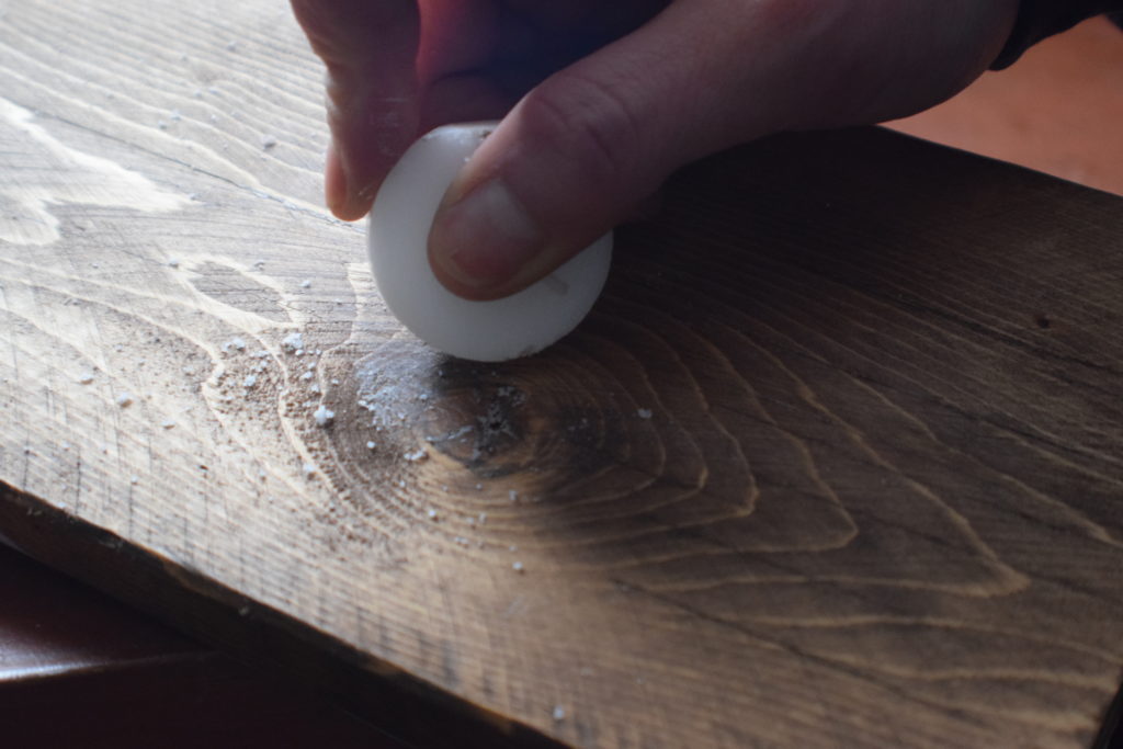 rubbing wax candle on wood surface to fill gaps