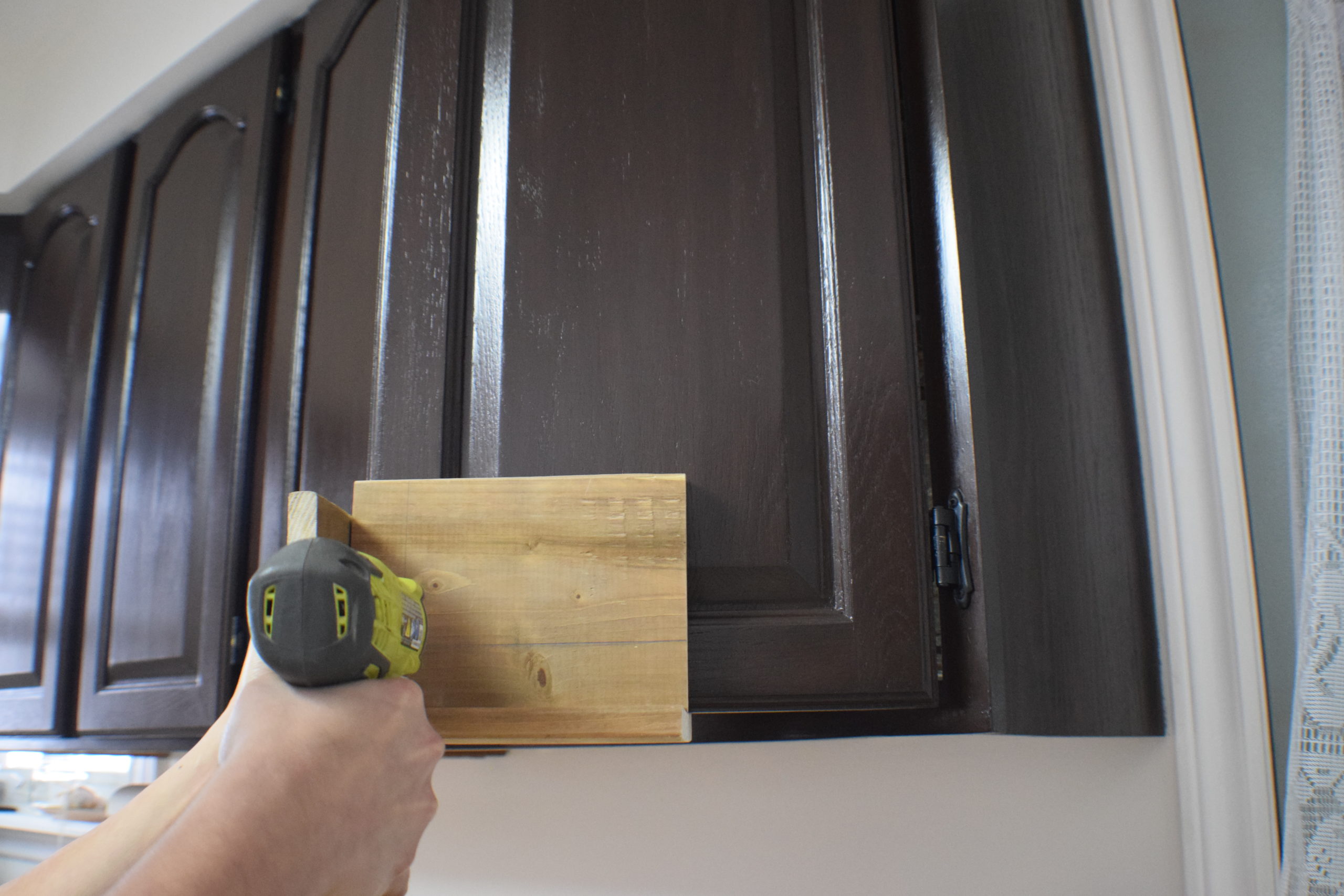 drilling through a wood jig on a kitchen cabinet door