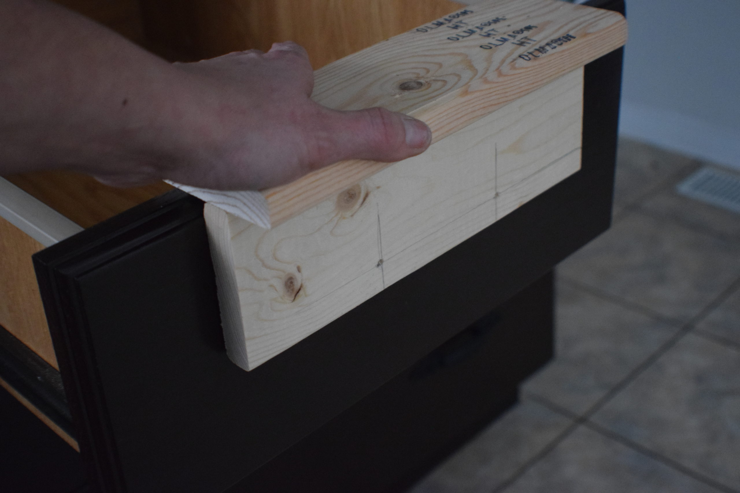 A cabinet drawer jig in place on a dark drawer