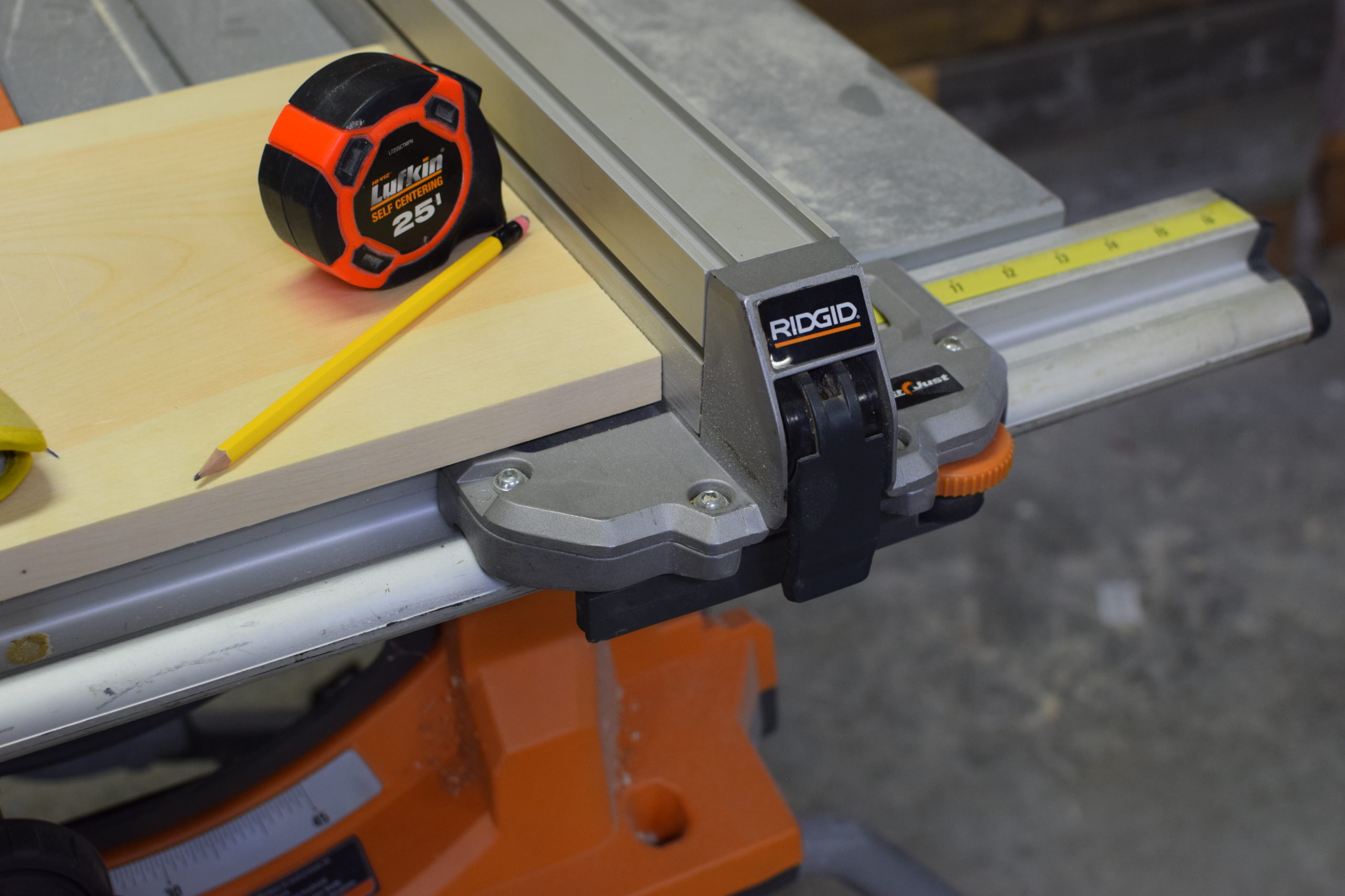 tape measure and pencil on top of wood on an orange table saw