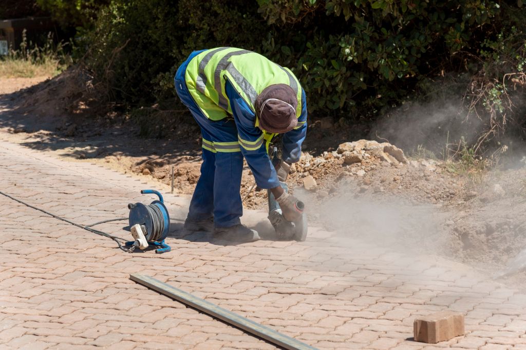 construction worker cuts through concrete sidewalk