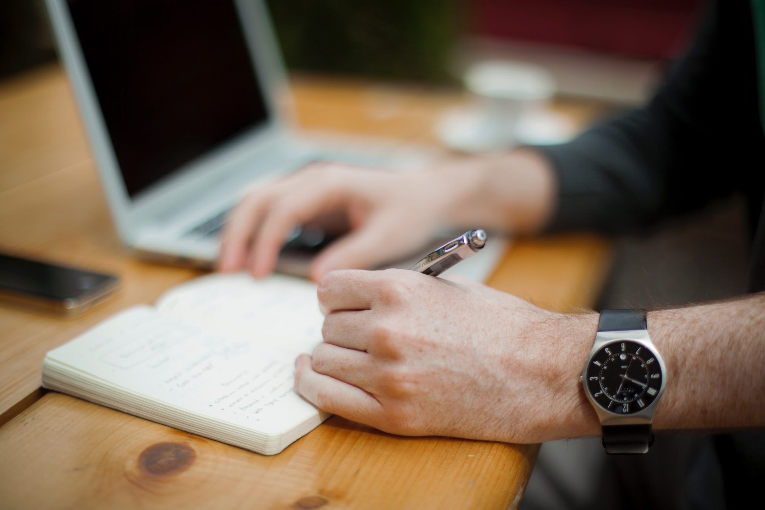 man with wrist watch writing on paper