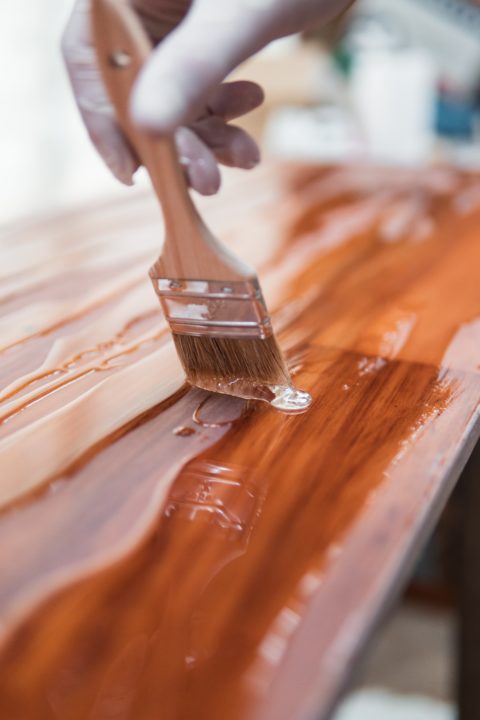 using a paint brush to apply stain on wood