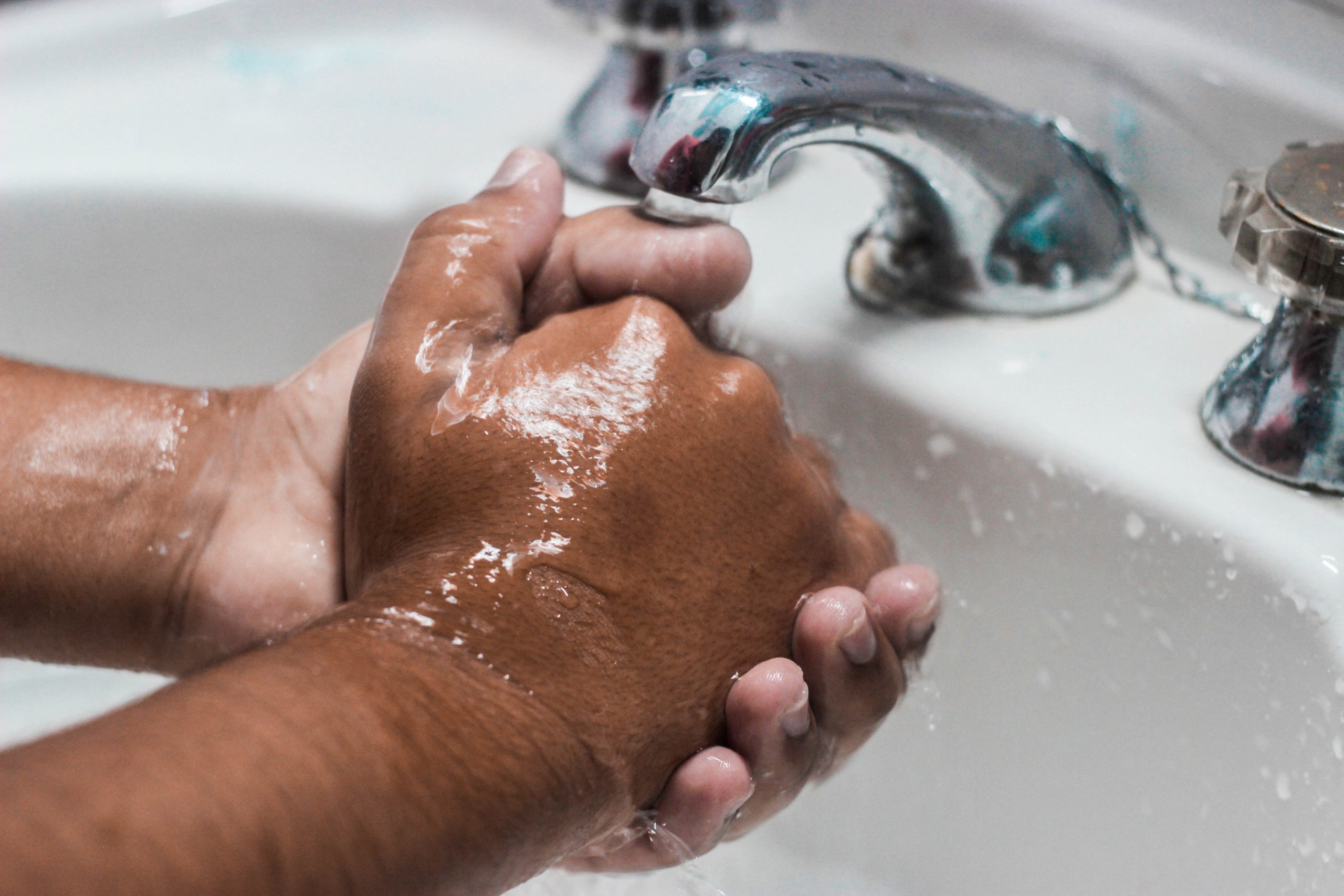 tanned man washing hands in sink