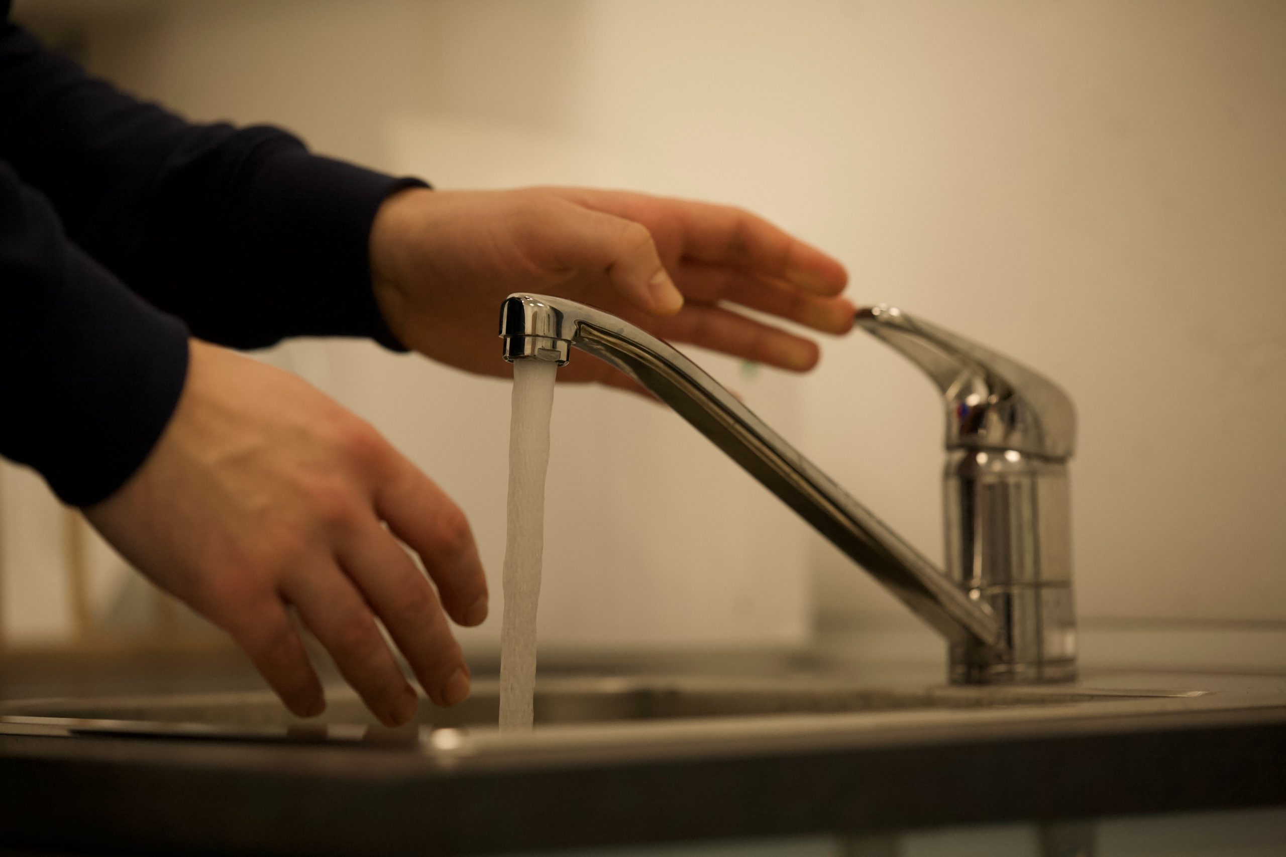 man turning off kitchen tap