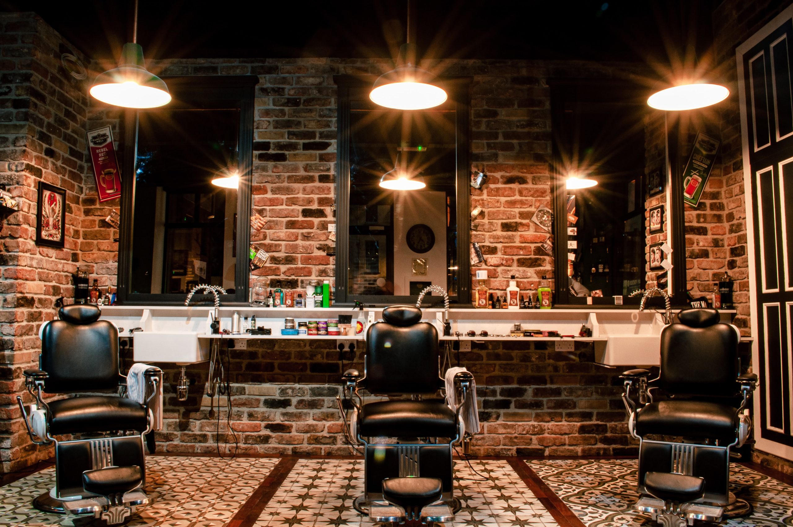 masculine barber shop with red mixed brick walls, mirrors, dim lights and tiled floor